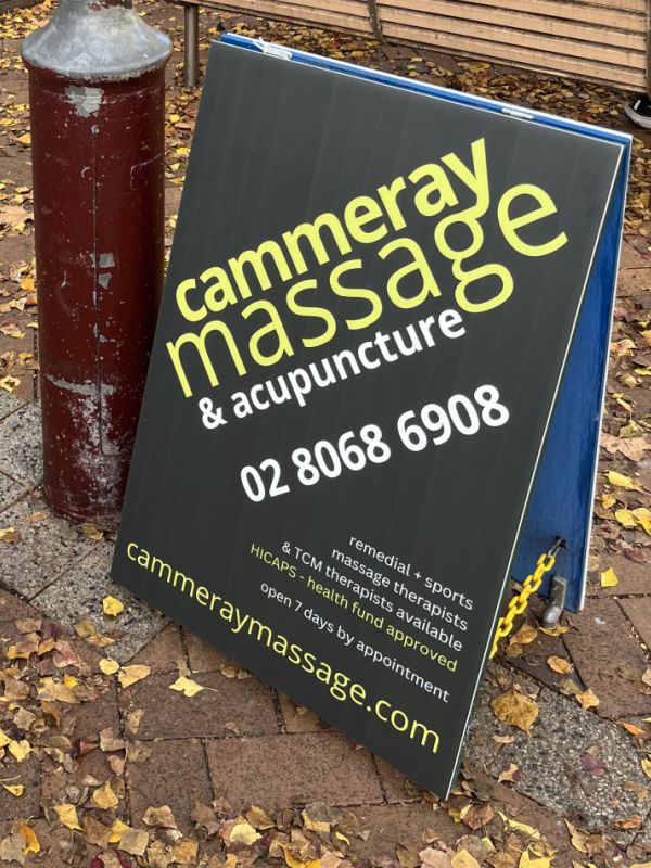 Cammeray Massage and Acupuncture signboard on Miller St footpath by Maggios advertising remedial and sports massage therapists, TCM massage therapists, HICAPS health fund approved, open 7 days by appointment.