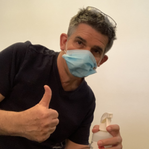 Jef wearing a mask, holding cleaning spray for Mask Policy Update